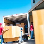 Movers near me efficiently loading furniture into a truck in a bright suburban setting.