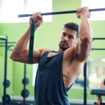 Active individual using a pull-up assist band in a bright gym, showcasing fitness and strength.